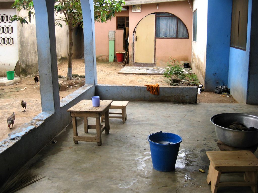 A shared courtyard in Ashaiman, a settlement outside of Accra, showing vessels of water for washing and bathing.